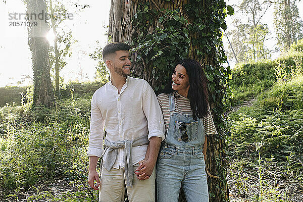 Happy couple holding hands standing in front of forest