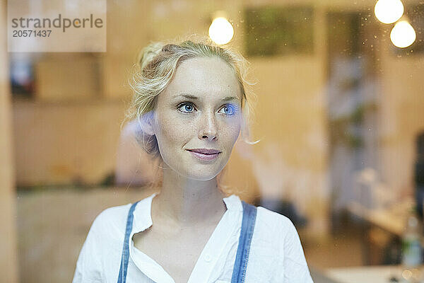 Smiling woman seen through glass in cafe