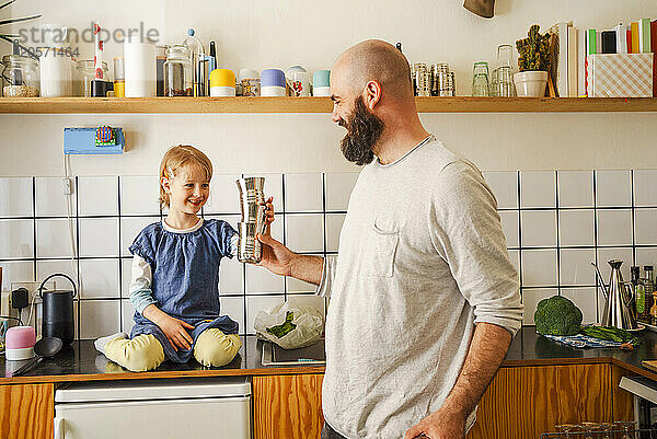 Father and daughter stacking glasses in kitchen at home