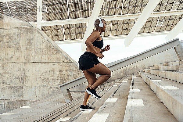 Determined sporty muscular woman jogging on steps