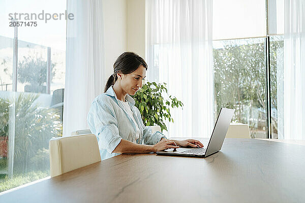 Confident businesswoman using laptop at table