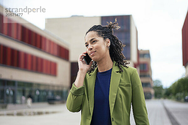 Beautiful young businesswoman talking on smart phone at office park