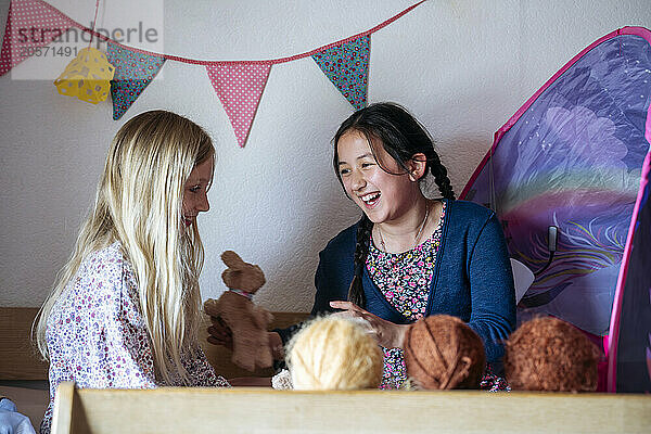 Happy multiracial girls playing together in bedroom at home