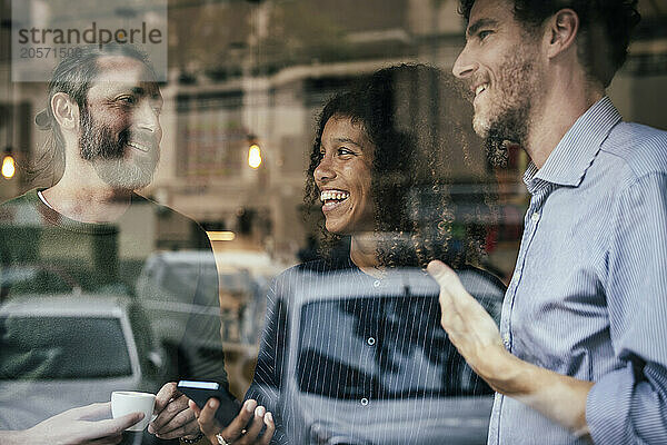 Happy business colleagues using smartphone in cafe