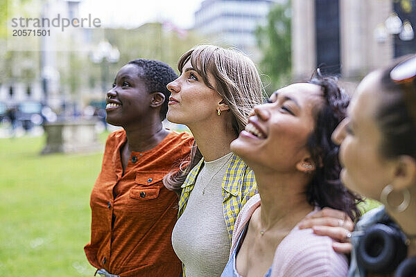 Multiracial female friends walking side by side at park