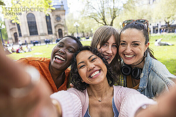 Happy woman taking selfie with multiracial female friends at park