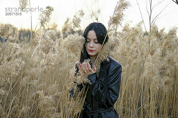 Woman cupping hands and holding crop at field