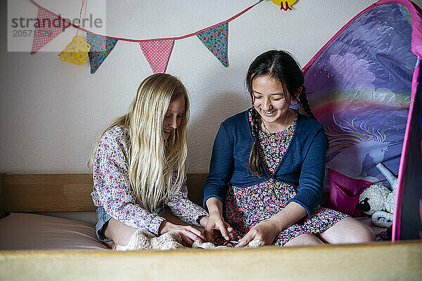 Multiracial friends playing together on bed at home