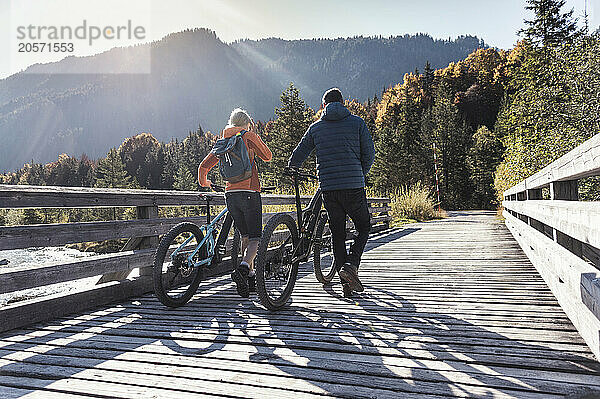 Couple with bicycles on boardwalk at weekend