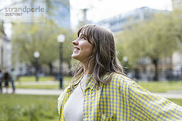 Smiling beautiful young woman wearing checked pattern shirt looking away at park