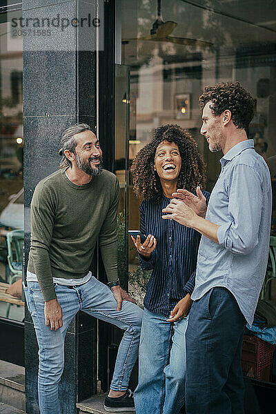 Happy business colleagues standing and laughing in front of cafe