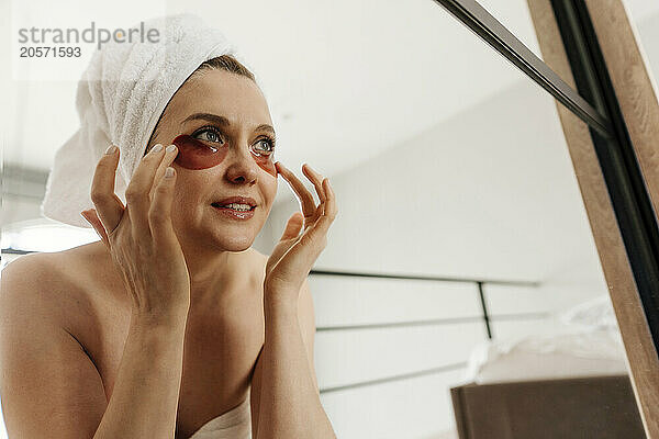 Woman with eye patches doing self care at home