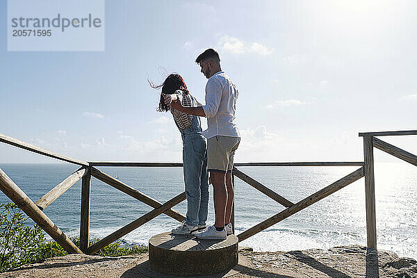 Boyfriend and girlfriend standing on sundial near railing