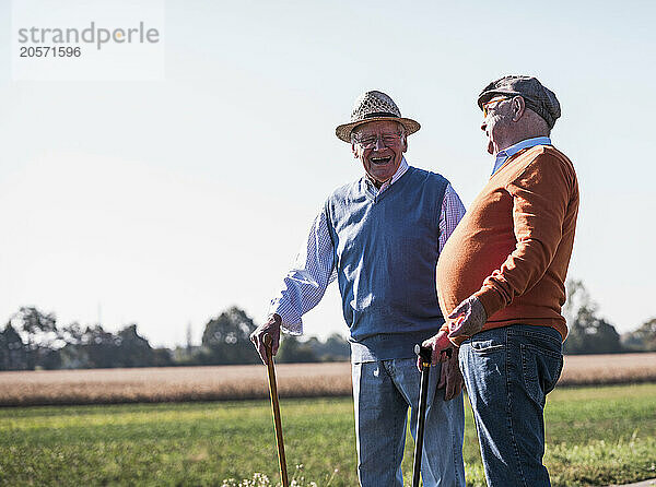 Happy friends laughing in middle of dirt road at field