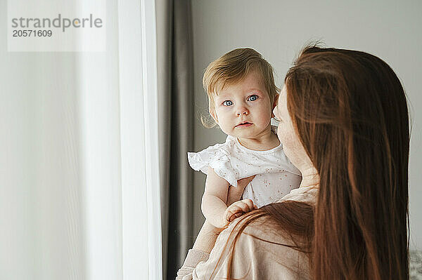 Redhead woman carrying toddler girl at home