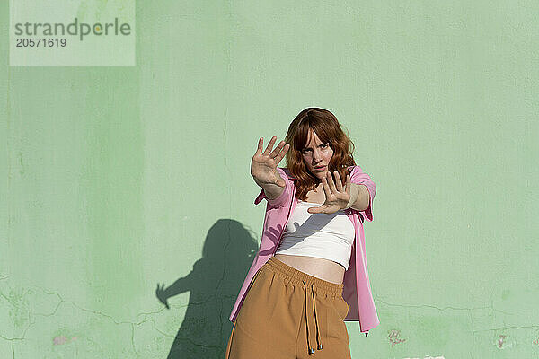 Confident woman dancing in front of mint green wall