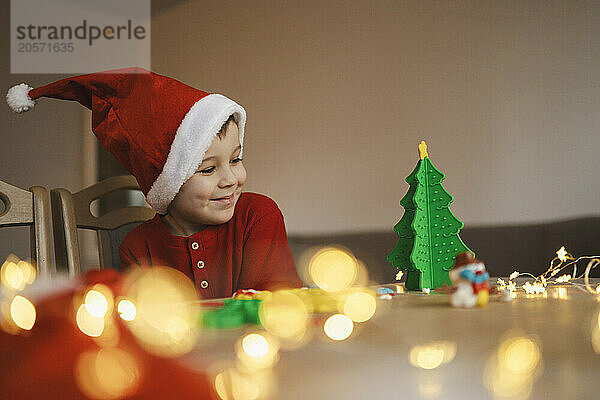 Happy boy looking at clay Christmas tree on table