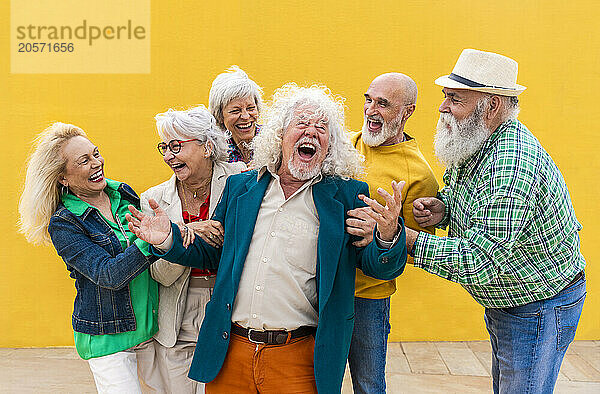 Cheerful senior men and women catching friend on footpath