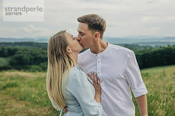 Romantic young couple kissing in meadow on mountain