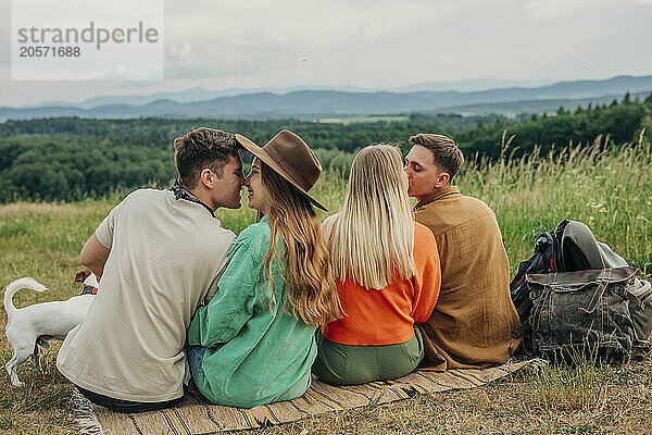 Group of romantic couples sitting on blanket in meadow at mountain of Poland