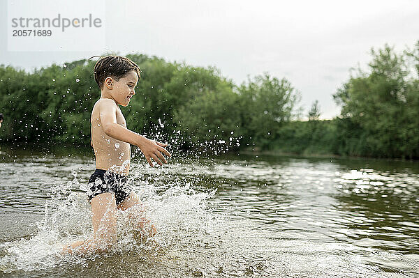 Shirtless boy splashing water in river