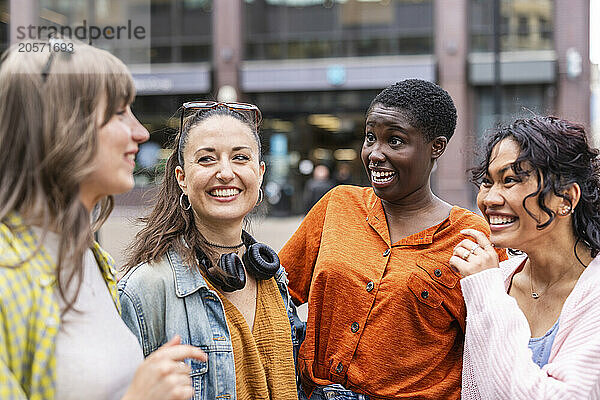 Cheerful female friends talking in city