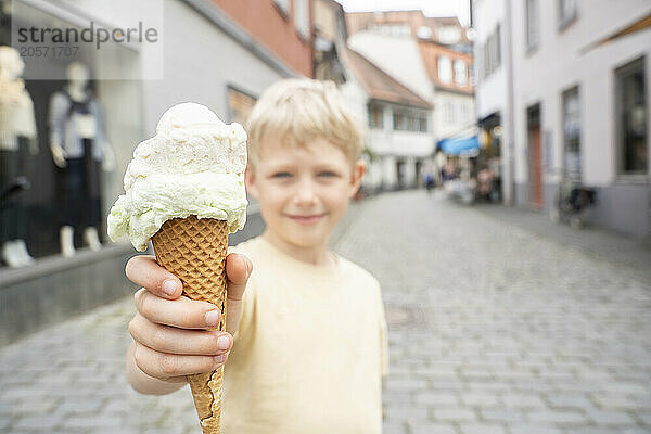 Happy boy holding ice cream on street in city