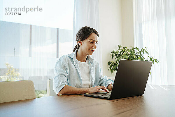 Smiling businesswoman using laptop at table