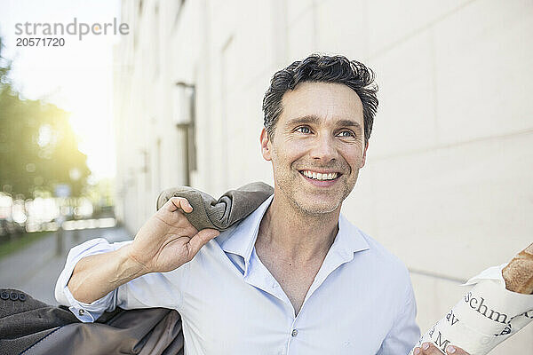 Happy businessman running with baguette and blazer