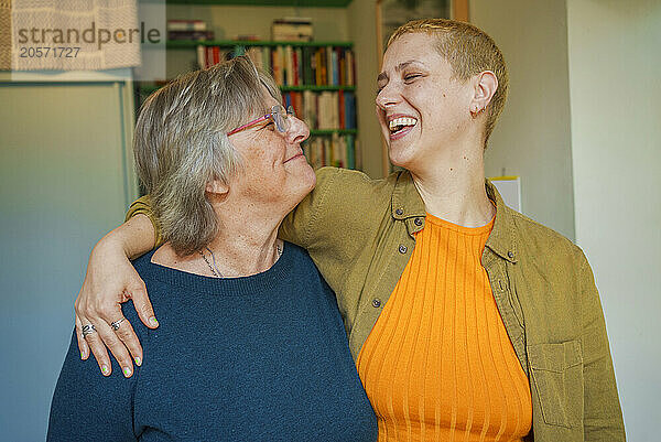 Cheerful woman with arm around mother at home