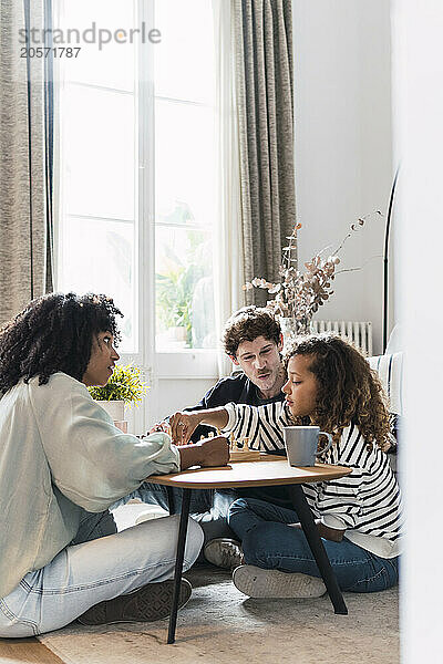 Parents sitting in livingroom teaching daughter to play chess