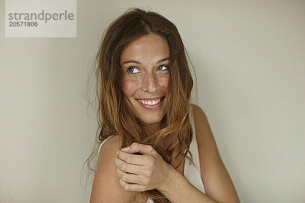 Smiling young woman in front of wall at home