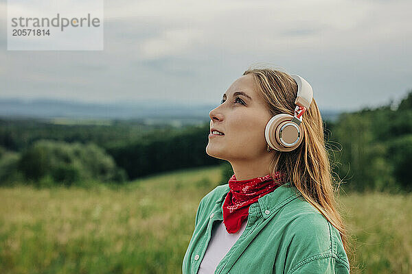 Beautiful young woman with wireless headphones listening to music on mountain