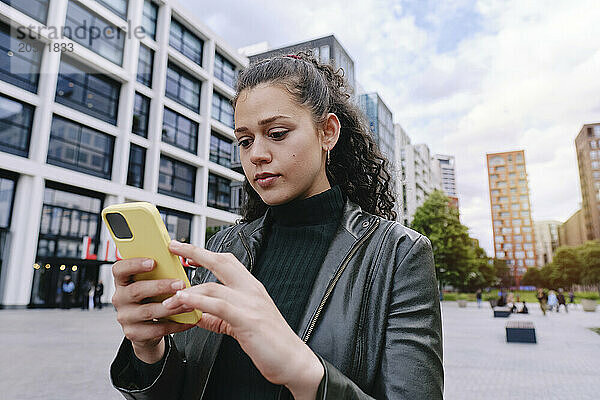 Young woman using smart phone in city