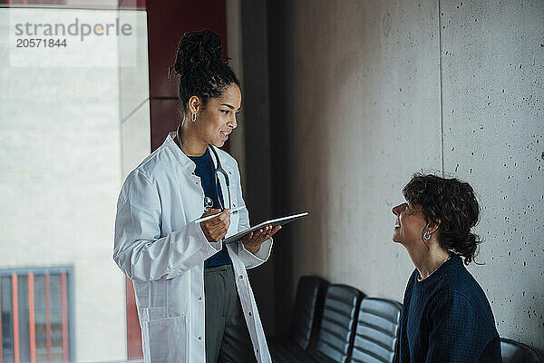 Doctor discussing with smiling patient in hospital