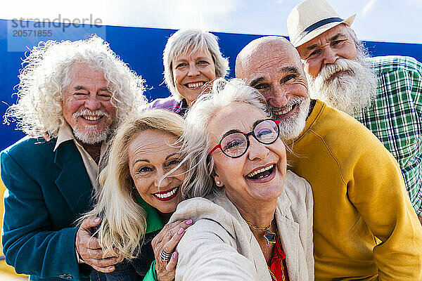 Happy elderly friends taking selfie on sunny day