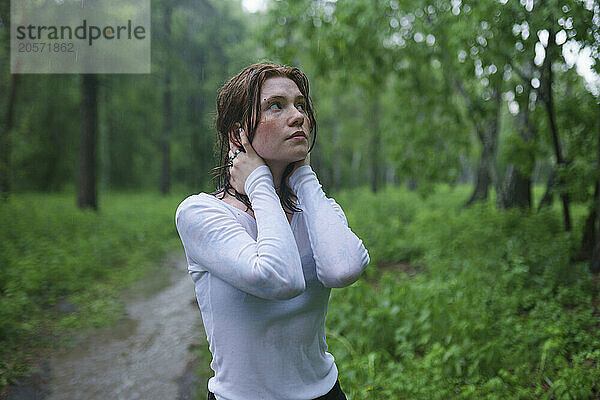 Woman standing in rain at forest