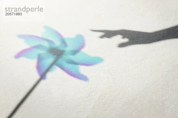 Shadow of woman's hand reaching pinwheel toy