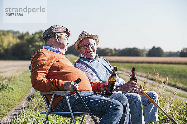 Happy friends enjoying drink at field