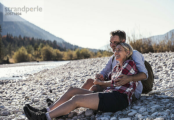 Happy mature couple sitting on pebbles