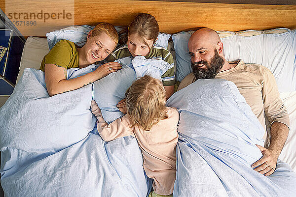 Happy family resting together on bed at home