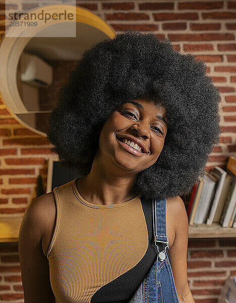 Smiling young woman with Afro hairstyle at home