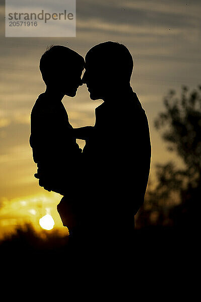 Silhouette of father and son at sunset