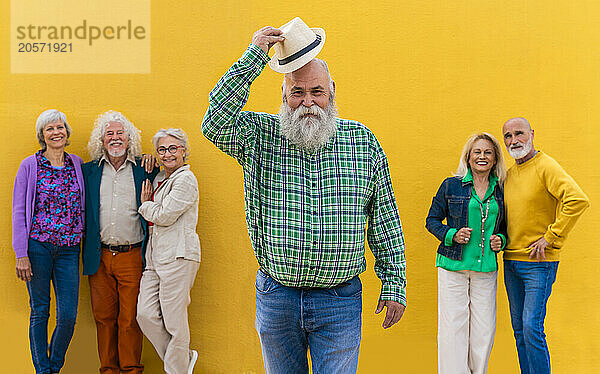 Confident senior man wearing hat with friends in background