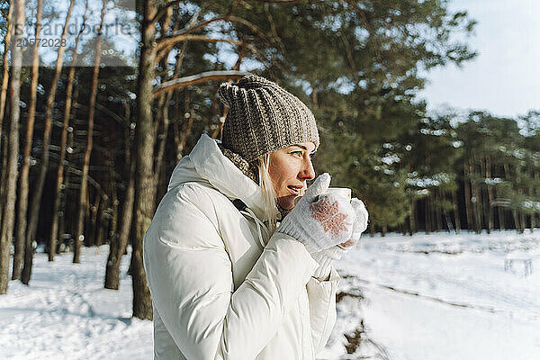 Woman in warm clothes drinking hot tea