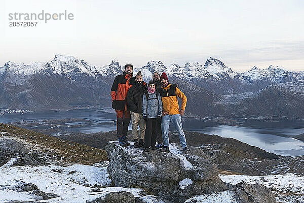 Friends standing and posing on rock near mountain range