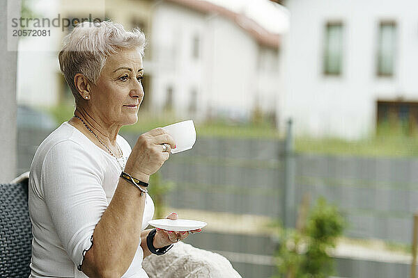 Thoughtful senior woman drinking coffee at patio