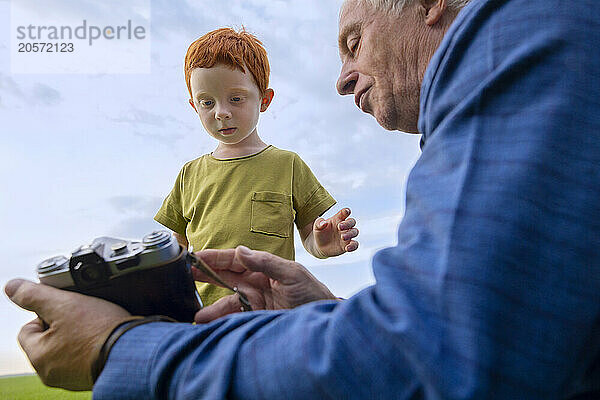 Elderly man shows his grandson old camera