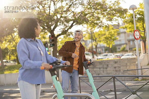 Happy young couple with electric push scooter at park