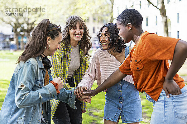 Cheerful multiracial women stacking hands at park